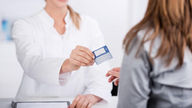Doctor handing insurance card back to patient